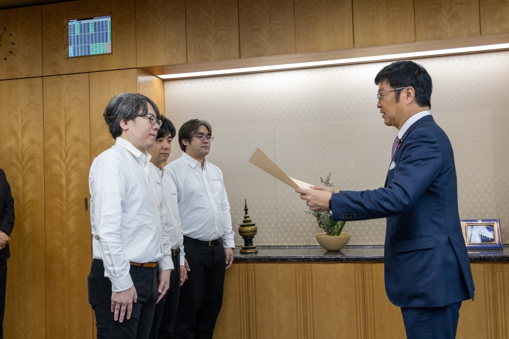 阿達雅志 総務副大臣より表彰状をいただいたHardening Project実行委員会の中津留勇、山城重成と安田真悟